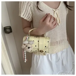 Detail of a cream polka dot pillow bag with a cute bear charm pendant and top handle