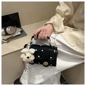 Detailed view of stylish black polka dot pillow bag with a cute teddy bear charm