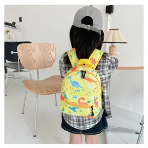 Back view of a child wearing a cute yellow backpack with colorful dinosaur prints in a room.