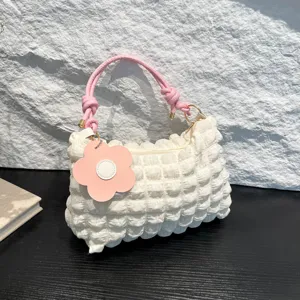 Stylish white pleated bubble handbag featuring pink knotted straps and a cute flower charm