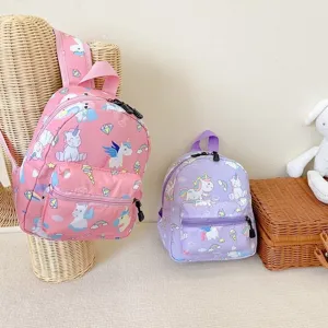 Detailed view of two cute pink and purple unicorn cartoon backpacks in a soft nursery setting