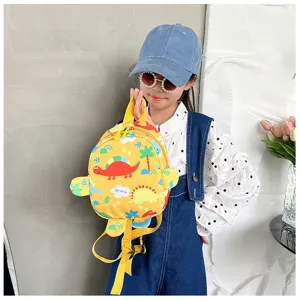 Cute yellow toddler backpack with cartoon dinosaur prints held by a child model