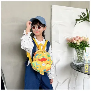 Adorable yellow kids backpack featuring dinosaur illustrations shown on a young model