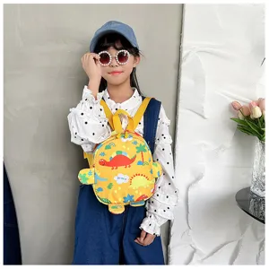Detailed shot of child wearing a cute yellow mini backpack with colorful dinosaur patterns