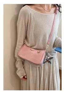 Pink matte suede underarm bag detail with star charm shown on a beige sweater