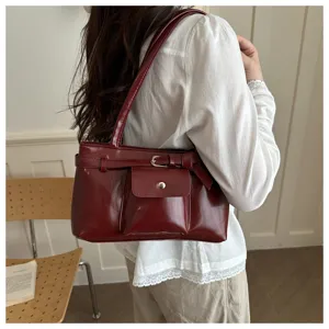Side view of a vintage burgundy textured shoulder bag featuring an elegant front pocket design