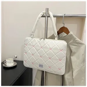 Gros plan sur un sac d'ordinateur blanc matelassé avec broderie de nœuds roses