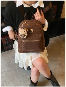 Detailansicht eines Vintage-Rucksacks mit Leopardenmuster, Plüschtier-Anhänger und Metallteilen