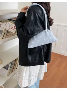 Close-up of a stylish light blue polka dot underarm bowling bag worn by a model