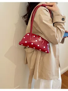 Chic red bowling handbag with white polka dots carried as a stylish underarm bag.