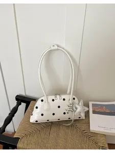 Detailweergave van witte bowlingtas met stippen en zilveren sterhanger en ballonhond