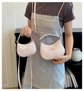 Vue détaillée d'un sac à bandoulière rose à pois et d'une mini pochette portés par un modèle