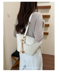 Dettaglio di un'elegante borsa tote bianco crema con ciondolo a fiore.
