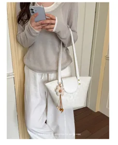 Borsa tote bianca minimalista in ecopelle con ciondolo a fiore, indossata da modella