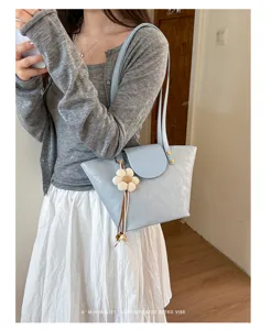 Dettaglio di una borsa a tracolla azzurra minimalista con un ciondolo a fiore decorativo