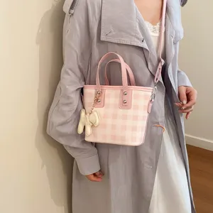Stylish pink and white gingham bucket bag with animal charm shown being worn by a model