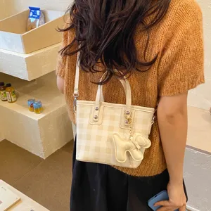 Detailed shot of a stylish cream gingham checkered small tote bag worn as a crossbody bag