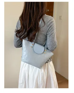 Vista posteriore di una borsa tote in pelle azzurra con borchie dorate indossata