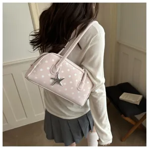 Stylish pink polka dot pillow handbag worn over the shoulder by a model in casual attire