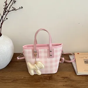 Stylish pink and white plaid bucket bag featuring a cute dog charm and crossbody strap