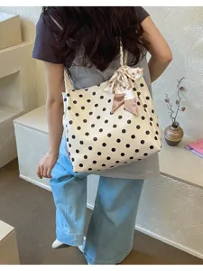 Casual polka dot tote bag with scarf detail worn by model in a minimalist setting
