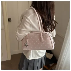 Pink polka dot pillow bag styled with a white sweater and grey pleated skirt detail view