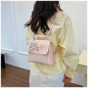 Sweet pink polka dot backpack for women featuring lace bow detail and heart charm decoration