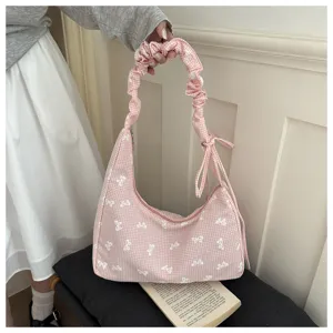 Detailed view of pink gingham shoulder bag with white bow pattern and scrunchie handle.