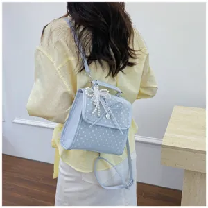 Back view of a light blue polka dot backpack with decorative lace bow and pearls