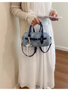 Stylish vintage blue denim pillow bag with star pendant held by model in white dress
