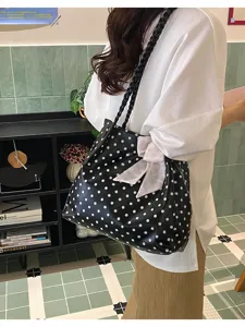 Lässige schwarze gepunktete Tragetasche mit rosa Schleife und geflochtenem Riemen