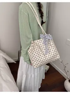 Polka dot tote bag with floral ribbon detail shown on a model in a cozy indoor setting.