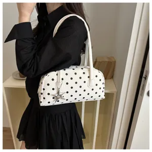 Trendy white pillow handbag with black polka dots and star charm carried by a model.