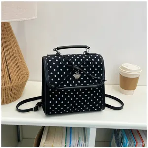 Detailed front view of a sweet black polka dot backpack with a bow and heart charm