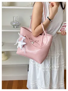 Elegant pink shoulder bag featuring bow detail and star charm in a lifestyle scene.