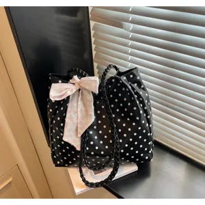 Große schwarze Tragetasche mit weißen Punkten, rosa Schleife und geflochtenen Trägern.