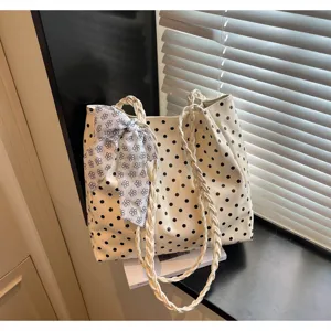 Detailansicht der cremefarbenen Polka-Dot-Tasche mit geflochtenen Griffen und Blumenschleife