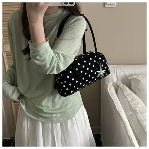 Woman carrying a stylish black polka dot pillow handbag with a silver star charm