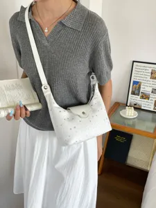 Sac à bandoulière blanc en forme de croissant avec motifs d'étoiles porté par un modèle
