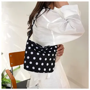 Elegante bolso de hombro de lona con lunares blancos y negros llevado por una modelo