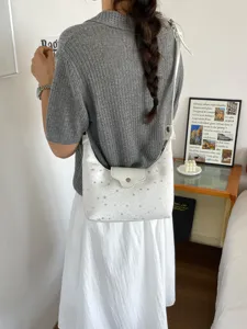 Sac à bandoulière blanc en forme de croissant avec motifs d'étoiles sur un mannequin