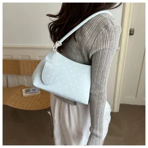 Bolso de hombro azul claro con lunares llevado por una modelo con top gris acanalado