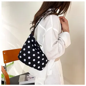 Vista lateral de un elegante bolso de cubo negro con lunares blancos llevado por una mujer