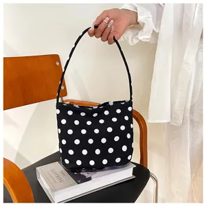 Vista detallada de un bolso cubo negro con lunares blancos sobre una silla decorativa