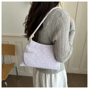 Bolso de hombro lila con lunares llevado con un suéter gris de canalé y falda blanca