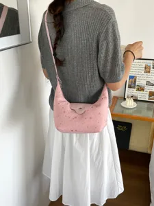 Vue détaillée d'un sac hobo rose en forme de croissant avec motifs d'étoiles porté par un mannequin.