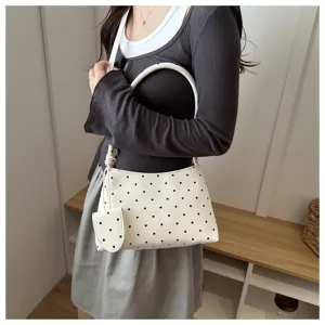 Primer plano de un elegante bolso blanco con lunares negros y monedero a juego