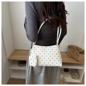 Bolso de hombro con lunares para mujer llevado por modelo en un interior chic.