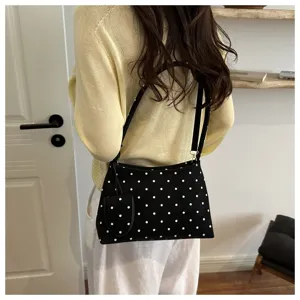 Vista trasera de una mujer con un bolso de hombro negro a lunares y su estuche.
