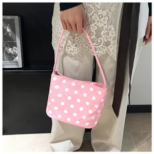 Primer plano de bolso tipo cubo rosa con lunares sostenido por una persona